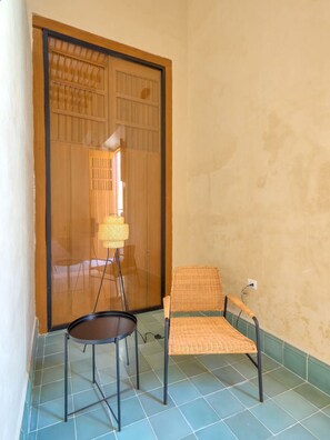 A room with a sliding door, a chair, a small table, and a floor lamp. - Loft w/bathroom and kitchenette + accessibility (Merida)