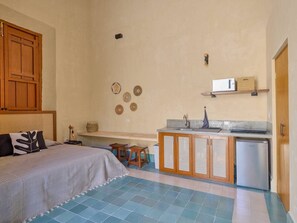 A bedroom with a bed, a wooden wardrobe, a small kitchenette with a refrigerator, and a bathroom with a toilet. - Loft w/bathroom and kitchenette + accessibility (Merida)