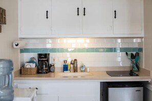 Eine Küche mit weißen Schränken, einer Kaffeemaschine, einem Wasserspender und einem Geschirrspüler.
