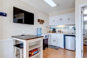 A compact kitchen with white cabinets, a microwave, a coffee maker, and a water dispenser.