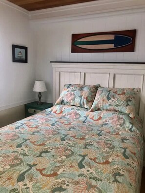 A bedroom with a bed, a nightstand, a lamp, and a wall-mounted directional sign.