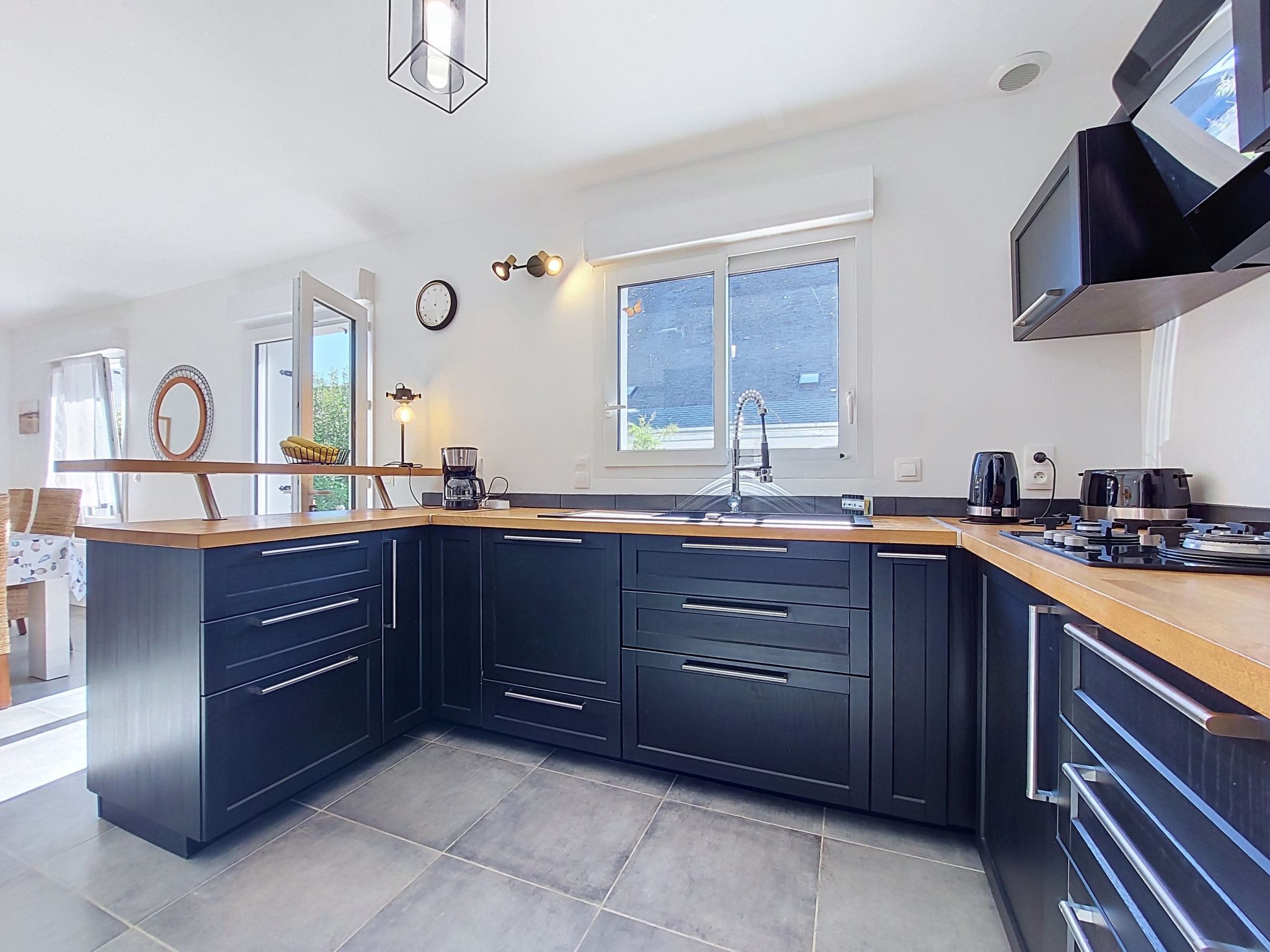 A modern kitchen with dark cabinetry, a wooden countertop, and a built-in oven.