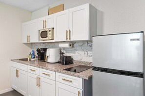 A kitchen with white cabinets, a stainless steel refrigerator, a coffee maker, and a microwave. - King Bed & WFH Setup - Pet Friendly 1BR Stay (Tampa)