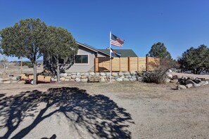 A house with a stone foundation, a wooden fence, and an American flag. - Mountain Retreat • Hot Tub • Sauna (Buena Vista)
