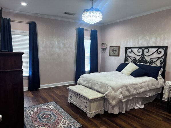 A bedroom with a bed, a dresser, a nightstand, a rug, and a chandelier. - Get away from the crowds 3-bedroom house in charming Northport neighborhood (Northport)