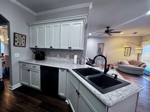 A kitchen with white cabinets, a black sink, and a herringbone-patterned backsplash. - Get away from the crowds 3-bedroom house in charming Northport neighborhood (Northport)