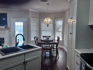 A kitchen with a double sink, wooden dining table, and a chandelier. - Get away from the crowds 3-bedroom house in charming Northport neighborhood (Northport)