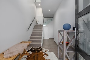 Ein modernes Interieur mit einer Treppe, einer Glastür und einer hölzernen Bank.