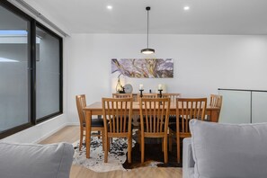Ein Essbereich mit Holztisch und -stühlen, einer Pendelleuchte und einem großen abstrakten Gemälde an der Wand.
