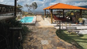 Un vialetto in pietra conduce a una piscina e a un'area salotto esterna con vista sul paesaggio.