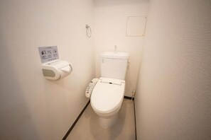 A small, white bathroom with a toilet, a paper towel dispenser, and a hand sanitizer dispenser. - goom Monthly Nakasu BLUGE (Fukuoka City Chuoku Haruyoshi)