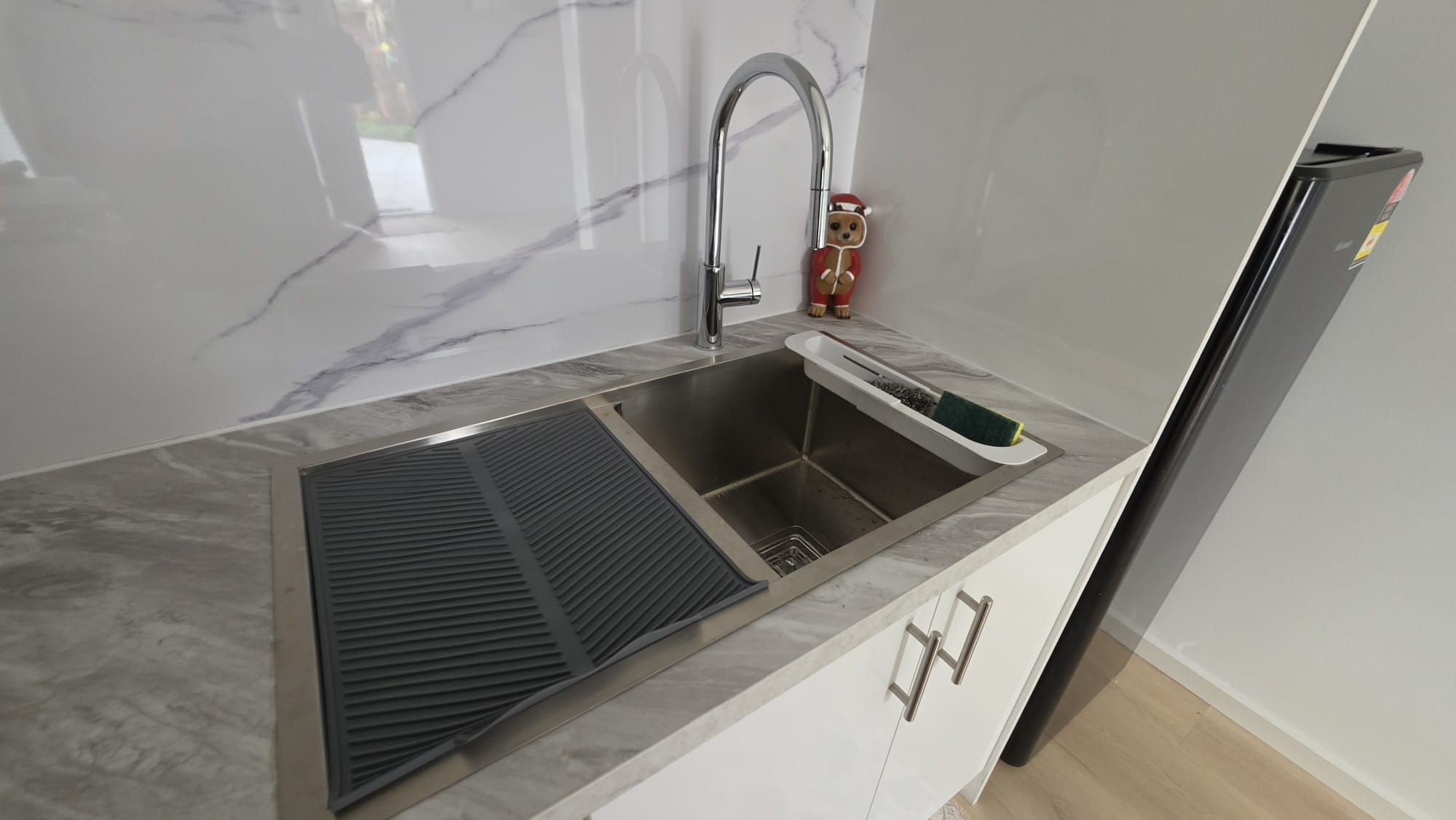 Eine Küche mit Spülbecken aus Edelstahl, integriertem Lüftungssystem und Kühlschrank.