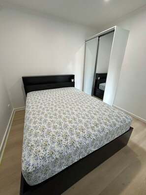 Ein Schlafzimmer mit einem Bett, einem Kleiderschrank und einem Spiegel.