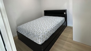 A single bed with a floral bedspread in a room with white walls and a wooden floor.