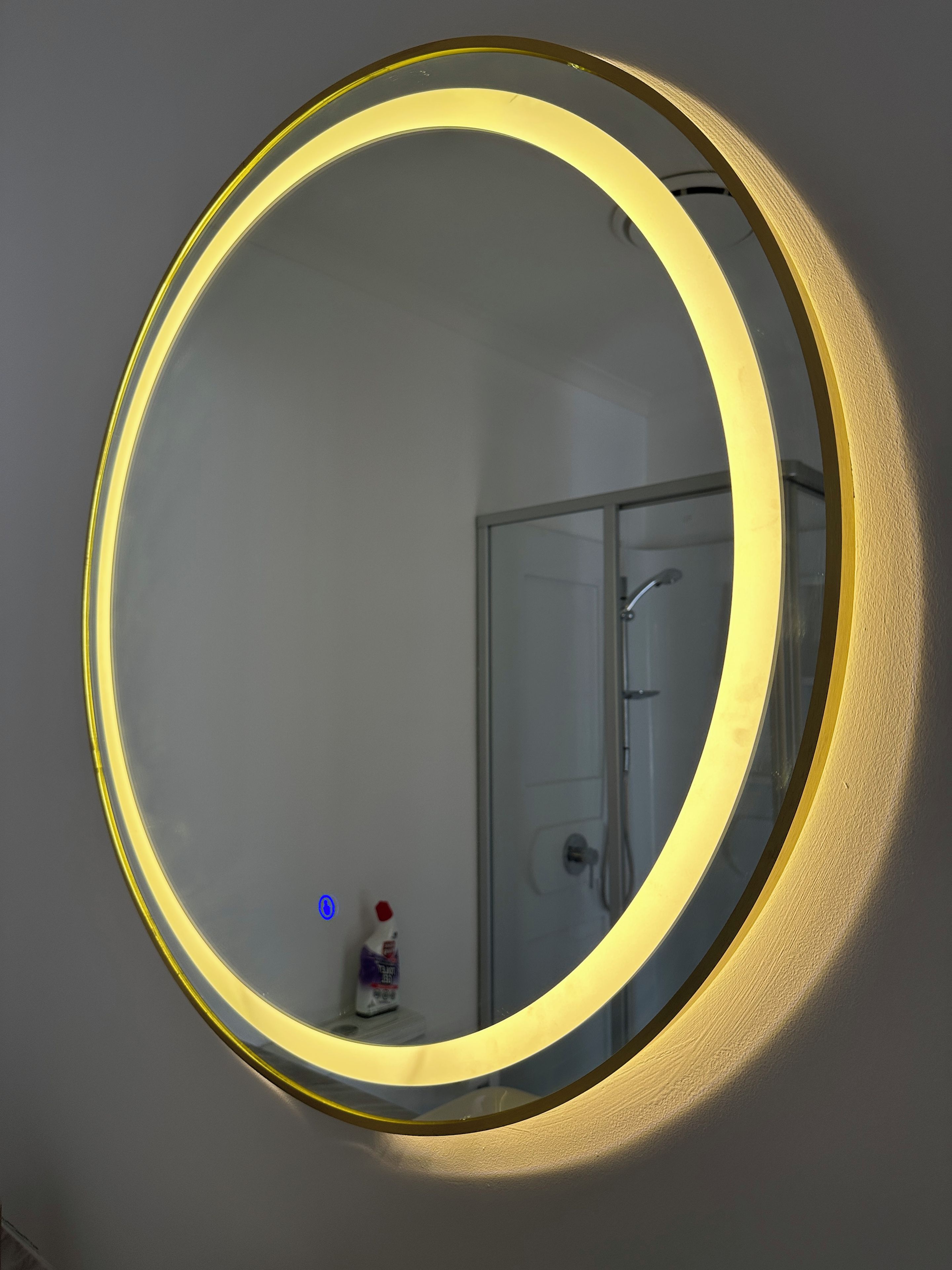 A round mirror with a golden frame mounted on a wall.