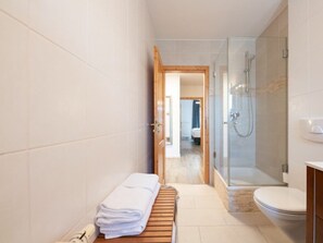 A bathroom with a shower, toilet, and a bench with towels. - Holiday Apartment With 1 Bedroom (Garmisch-Partenkirchen)
