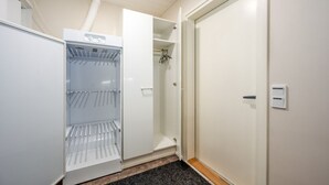 Et hotelværelse med et indbygget minikøleskab, et klædeskab og en dør med lyskontakt.