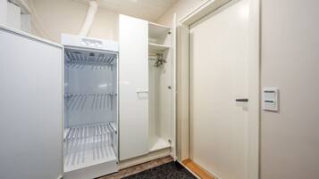 Ein Hotelzimmer mit eingebauter Minikühlschrank, einem Kleiderschrank und einer Tür mit Lichtschalter.