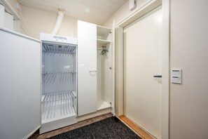A hotel room with a built-in mini-fridge, a wardrobe, and a door with a light switch.