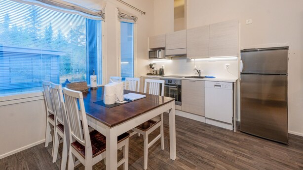Et moderne k økken med spisebord, stole, køleskab og mikroovn.