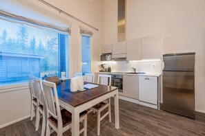 Eine moderne Küche mit Esstisch, Stühlen, einem Kühlschrank und einer Mikrowelle.