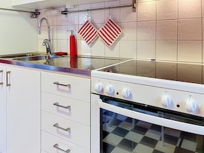 A kitchen with a stainless steel sink, a white stove with oven, and a checkered floor. - Villa Stensborg by Interhome (Östra Ryd)