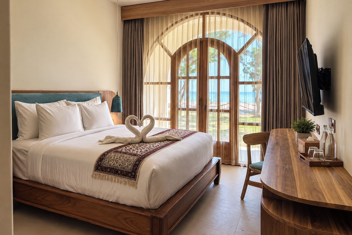 A hotel room with a bed, a wooden desk, a chair, a TV, and a window with curtains.
