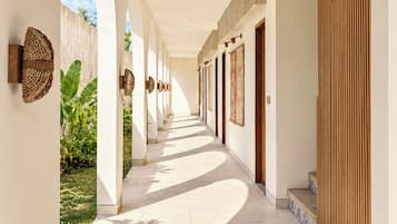 A corridor with arches, tiled flooring, and a view of greenery outside.