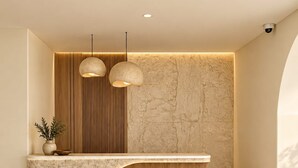 Una reception con finitura in legno e un piano in marmo. Due lampade a sospensione illuminano l'area.