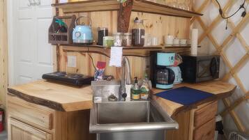 A compact kitchen with a sink, a coffee maker, and a microwave.