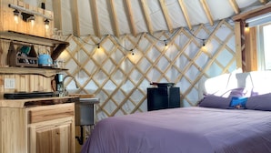 A cozy room with a bed, wooden cabinets, and a unique lattice wall design. - A cozy yurt with all of the amenities (Big Lake)