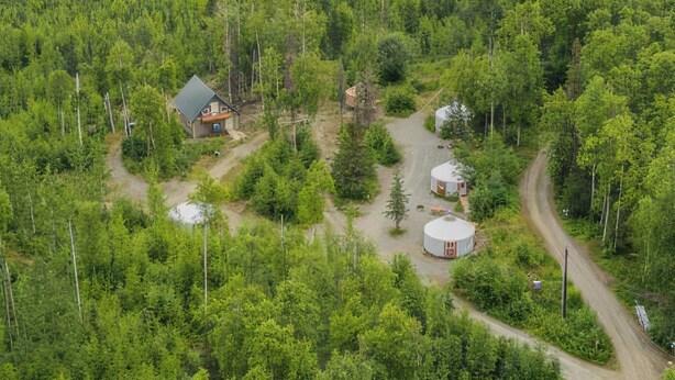 A remote cabin surrounded by dense forest, with a dirt path leading to it. - A cozy yurt with all of the amenities (Big Lake)