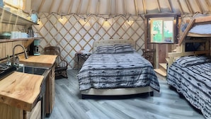 A cozy yurt with a bed, a small table, and a TV. - A cozy yurt with all of the amenities (Big Lake)