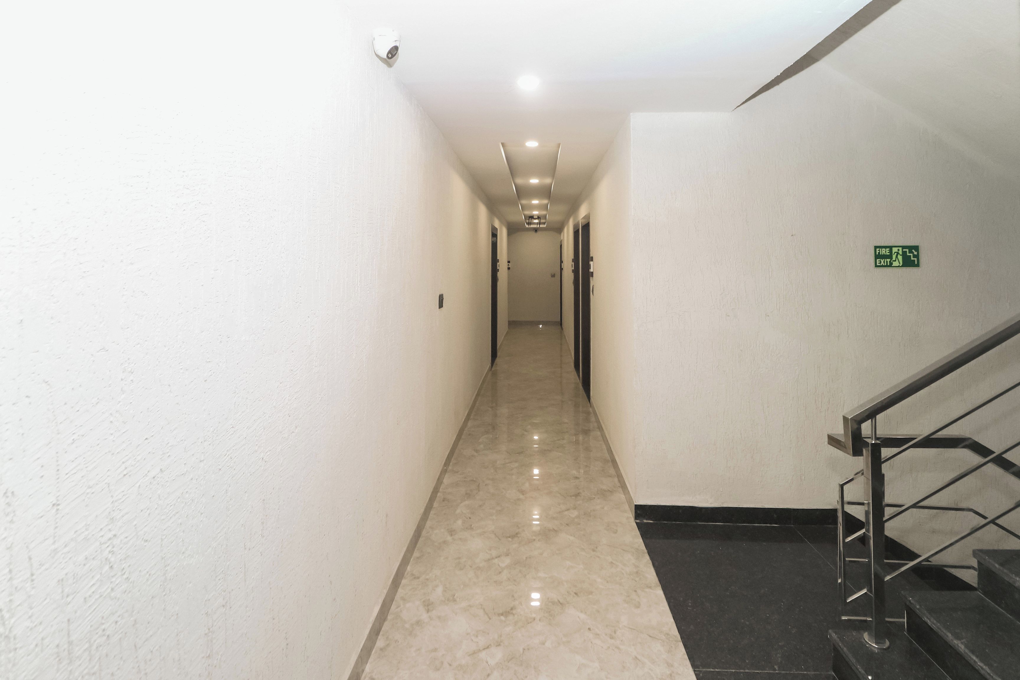 A long, narrow hallway with a marble floor leading to a staircase.