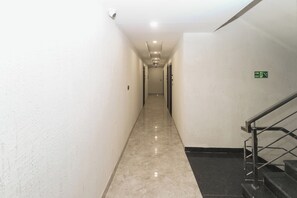 A long, narrow hallway with a marble floor leading to a staircase.