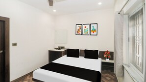 A hotel room with a bed, a desk, a chair, a window, and a ceiling fan.