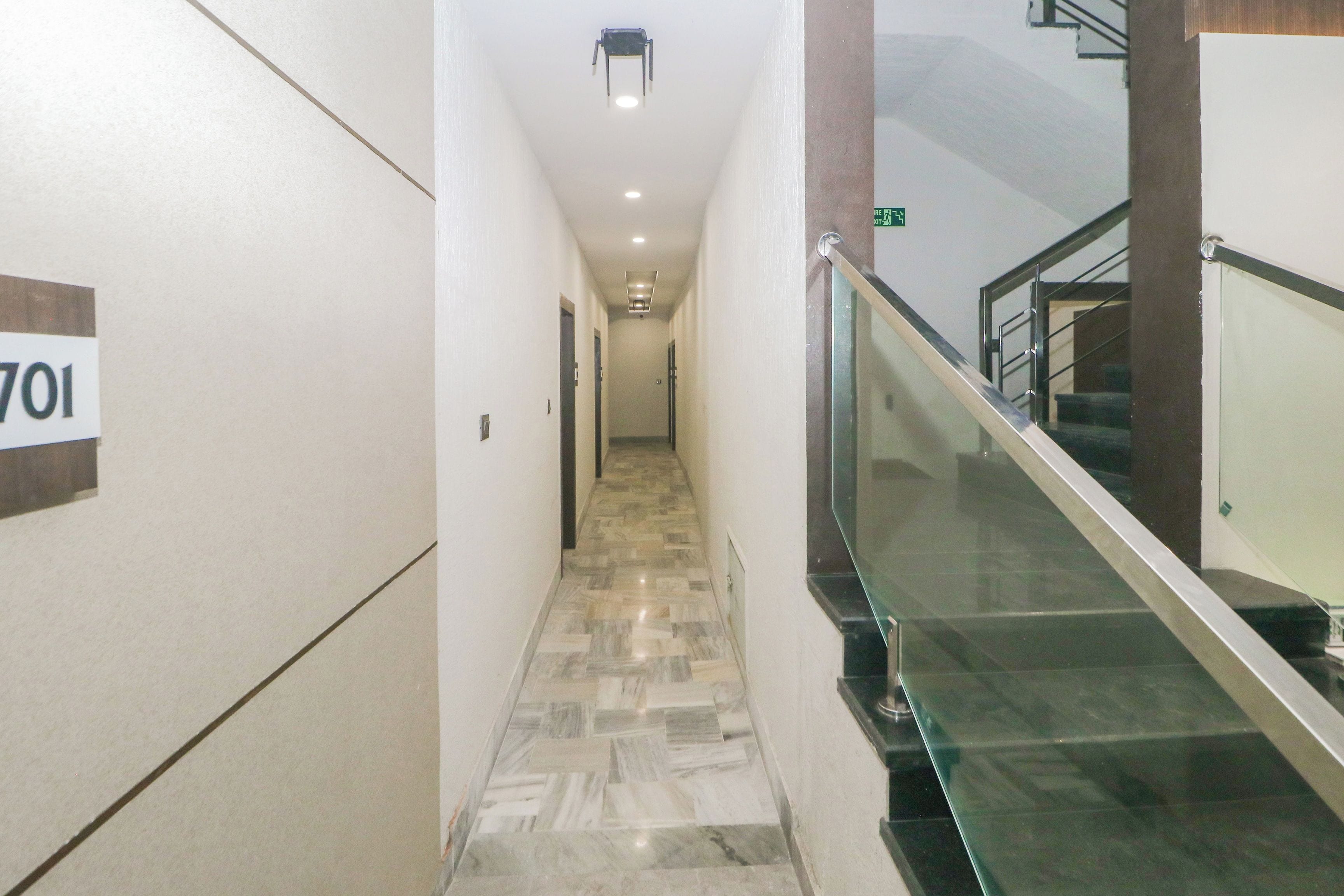 A hallway with a marble floor, a glass railing, and a sign indicating room number 701.