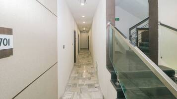A hallway with a marble floor, a glass railing, and a sign indicating room number 701.