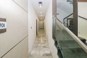 Un pasillo con piso de mármol, barandilla de vidrio y un letrero que indica la habitación 701.