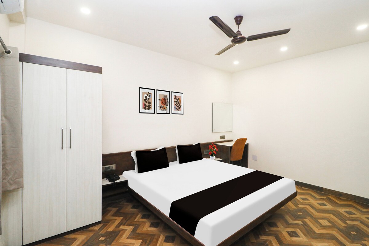 A bedroom with a bed, a wardrobe, a ceiling fan, and a wall-mounted mirror.