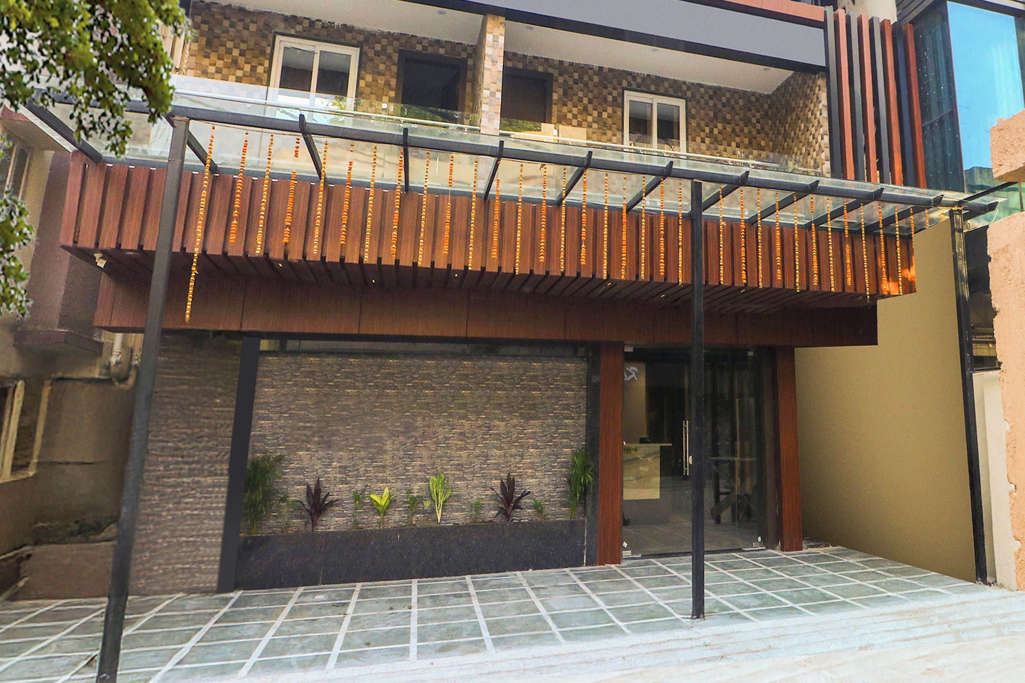 A modern building with a covered patio area, a brick wall, and a tiled entrance.