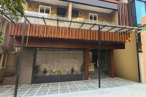 Un edificio moderno con un patio cubierto, un muro de ladrillo y una entrada con baldosas.