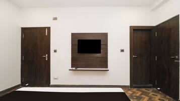 A bedroom with a large bed, a TV mounted on the wall, and two wardrobes.