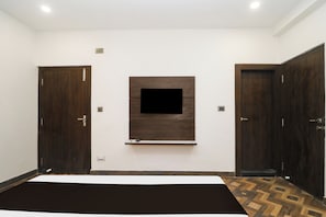 A bedroom with a large bed, a TV mounted on the wall, and two wardrobes.