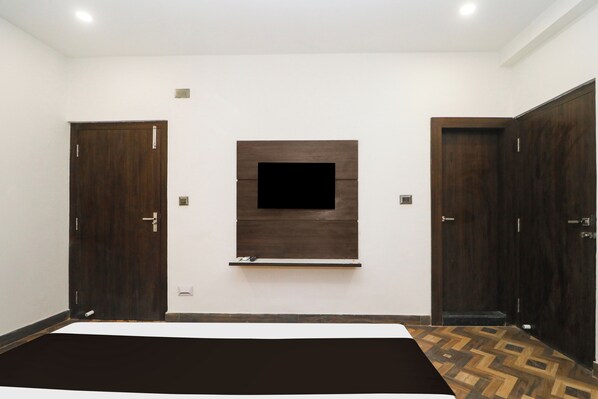 A bedroom with a large bed, a TV mounted on the wall, and two wardrobes.