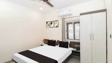 Une chambre à coucher avec un lit, une armoire, une fenêtre avec des barreaux et un ventilateur de plafond.