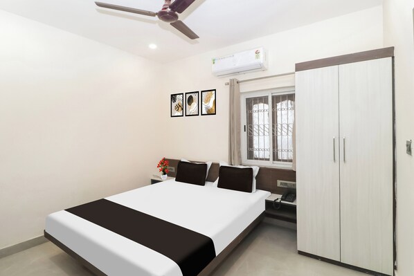 Un dormitorio con cama, armario, ventana con rejas y ventilador de techo.