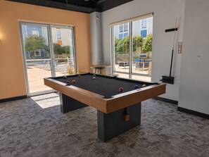 A pool table with balls, a window, and a door leading outside.