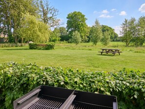 A grassy outdoor area with a barbecue grill, picnic table, and various trees. - Rust, space, and comfort in Balen. (Balen)