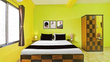 Une chambre d’hôtel avec un lit, une table de chevet, une lampe, une armoire et deux tableaux encadrés au mur.